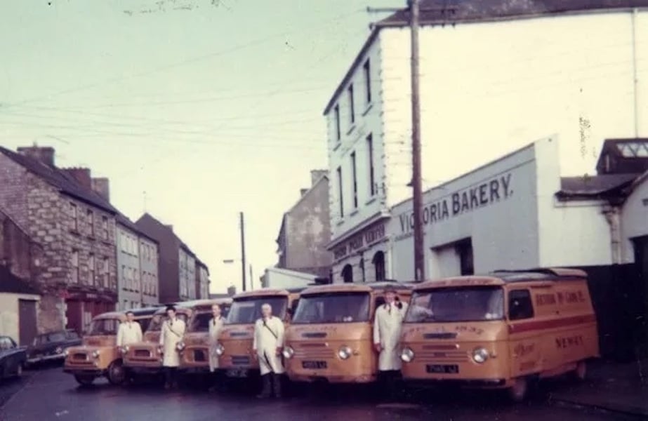 The orange delivery vans of McCann’s Bakery were a familiar sight in Newry, south Armagh and south Down in the 1960s. They are shown here, with the bread servers, in front of the Bakery building before Castle Street was demolished in the late 1960s.