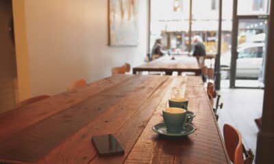 A cafe with a phone phone and cups of coffee on an empty table